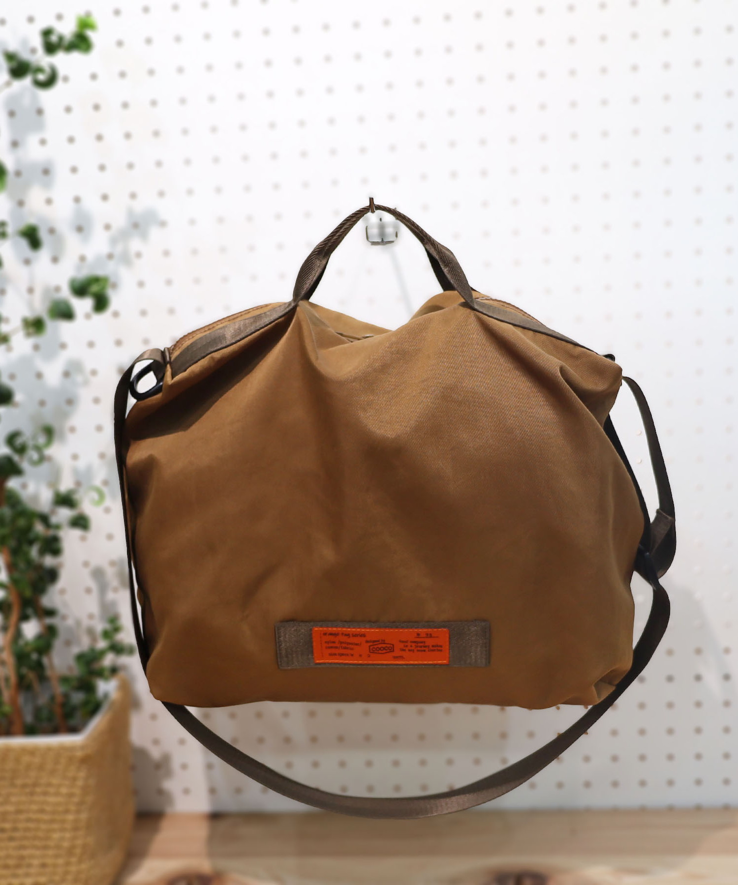 COOCOオリジナルORANGETAGを使用したBAGシリーズ。表地は撥水効果のあるツイルのナイロン生地を使用しました。ハンドル・ショルダー部には丈夫で軽量なポリエステルテープを使用。ハンドルは短めですっきりとした見た目に。ショルダー持ちした際に収まりよくデザインされています。