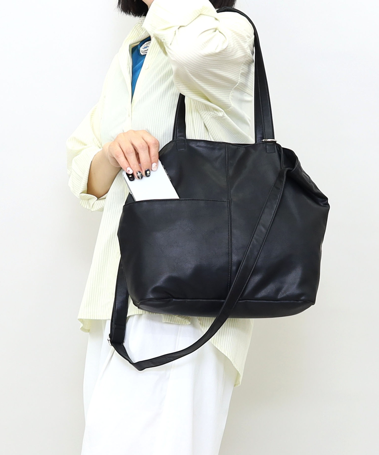 くたっとした柔らかいフェイクレザーを使用した大き目トートバッグです。このサイズのバッグで約350ｇと軽量なのが嬉しい！ハンドルは長めにしており、ストレスなく肩に掛けやすい設定です。さらに使いやすく、ロングショルダーもつけましたので、斜め掛けで使用することも可能です。前面には便利なポケット、内装にも3カ所ポケットを完備。収納に便利です。ハンドルにはお気に入りのチャームなどを下げれるように、丸形のカラビナをつけました。A4サイズもしっかり入るサイズ感ですので、いろいろなシーンで使いやすいバッグです！